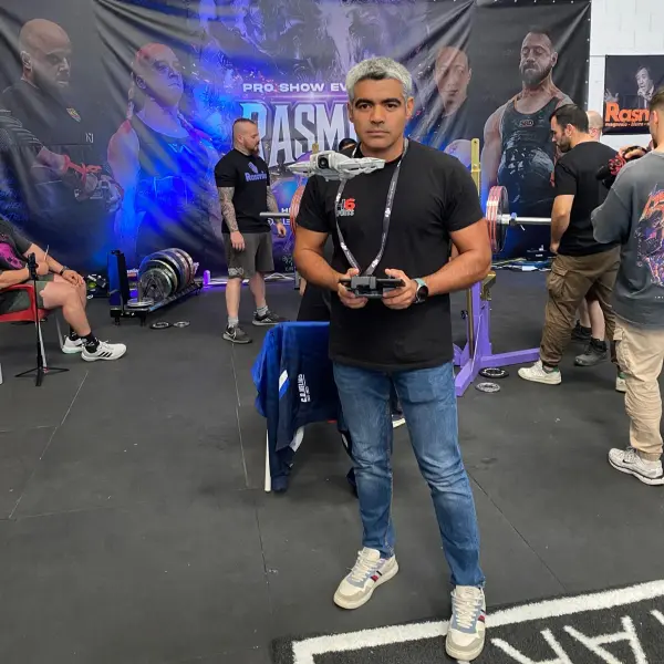 Operador de dron controlando un vuelo en un evento deportivo de fuerza, representando el uso de drones en competiciones con H6 Sports.